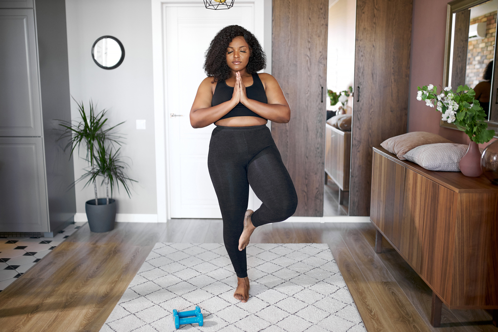 black woman doing yoga in her living room